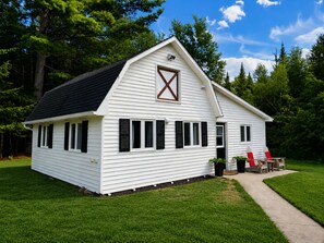 A white single-story house with a gabled roof and a prominent barn door window.