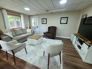 A living room with a sofa, chairs, a coffee table, a television, and a fireplace. - White Pine Cottage- Family Friendly, Play Structure, Huge Yard and Serenity (Richibucto Road)