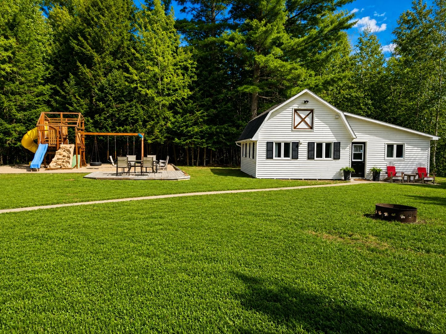 A white house with a porch and a swing set in a grassy yard.