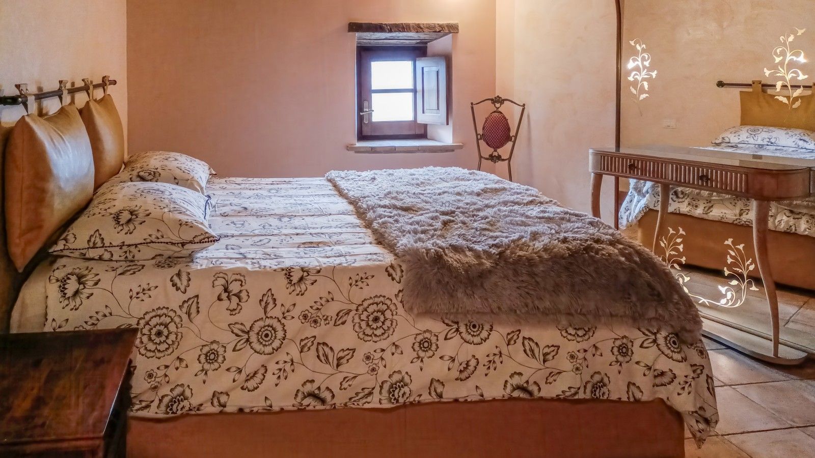 Un dormitorio con cama, ventana, silla y una mesita.