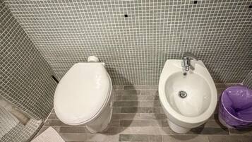 Een badkamer met toilet, hygiëneschuimer en een vuilnisbak.