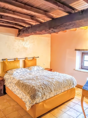 A bedroom with a bed, wooden ceiling beams, a window, and a nightstand. - Domus Claudia - Castiglione in Teverina (Castiglione In Teverina)