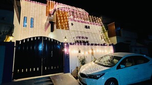 A modern house with a black gate, a car parked in front, and decorative lights. - Feel Like Home in a Luxury, Secured and Peaceful 2 Story House (Karachi)