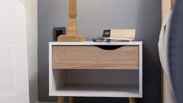 A bedside table with a lamp, a book, and a small electronic device.