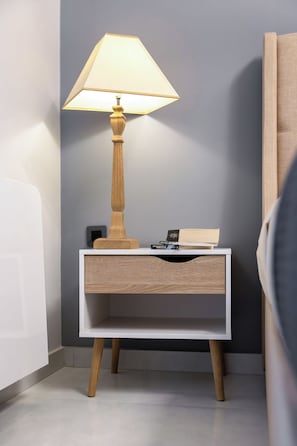 A bedside table with a lamp, a book, and a small electronic device. - Odyss Residence Ioannina (Ioannina)