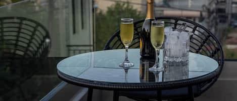 A table with a bottle and glasses on a balcony overlooking a town and mountains.