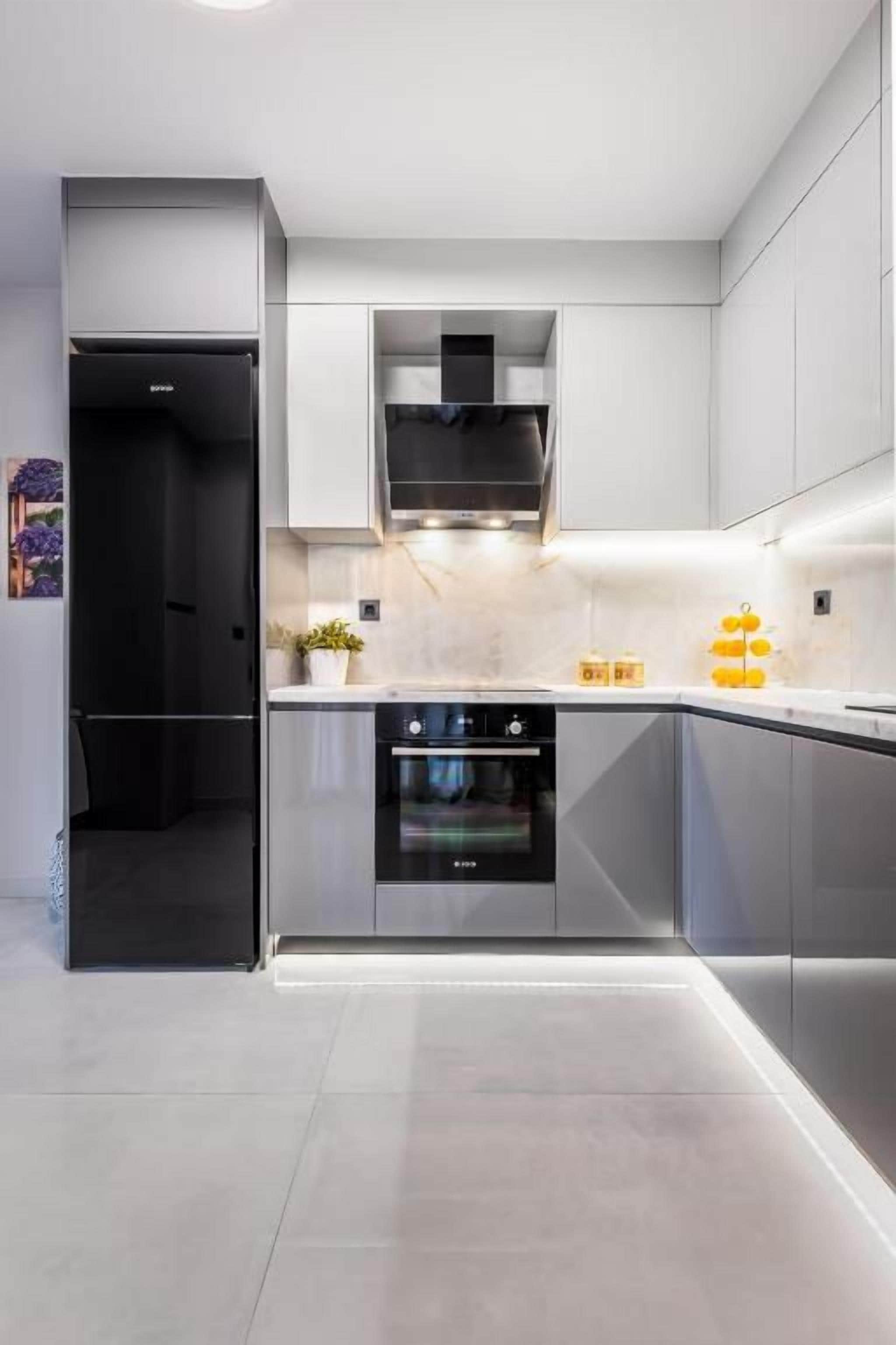 A modern kitchen with stainless steel appliances, a built-in oven, and a marble countertop.