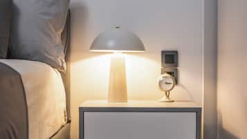 A modern bedroom with a bed, a bedside table with a lamp, and a wall-mounted clock.