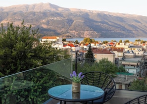 A balcony with a glass table and chairs, overlooking a town with buildings and mountains in the distance. - Odyss Residence Ioannina (Ioannina)
