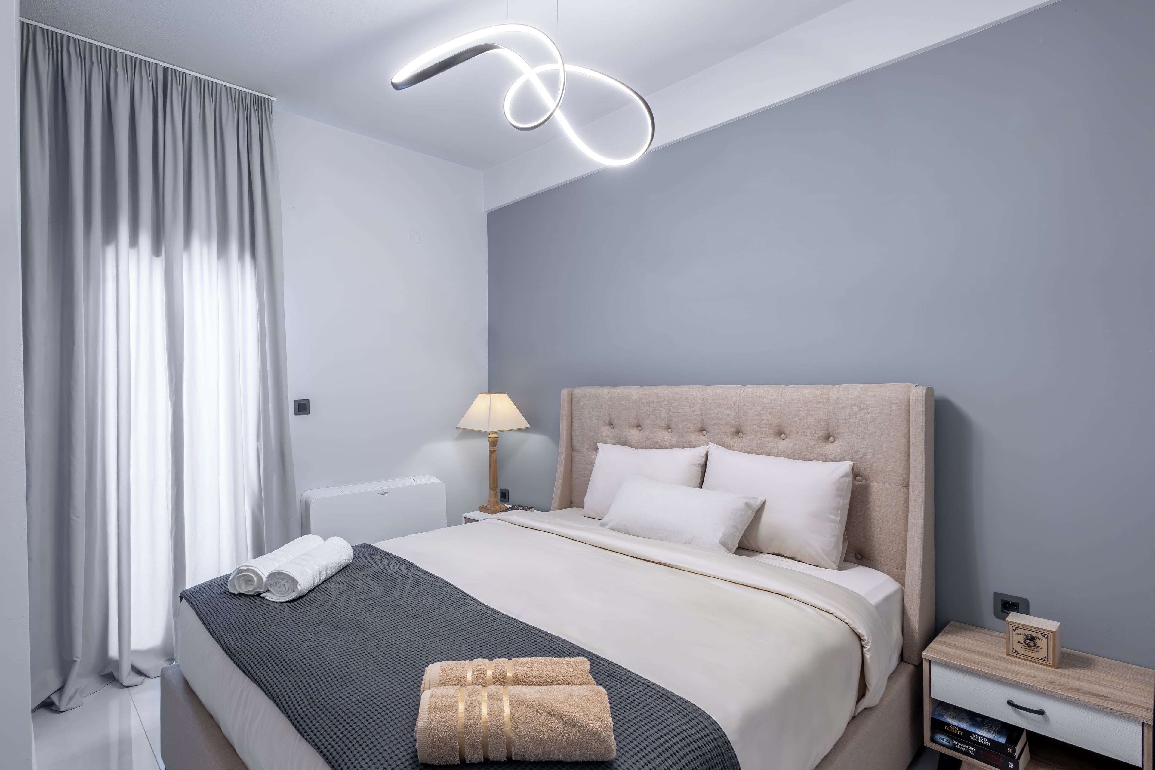A modern bedroom with a bed, bedside table, lamp, and a decorative ceiling light.
