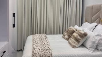 Un dormitorio moderno con cama, cortinas y una lámpara original.