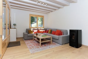 A modern living room with a grey sofa, a wooden coffee table, and a black fireplace. - Jacques’s Treasure: A cosy, renovated chalet in the Chartreuse (Saint-Pierre-d'Entremont)