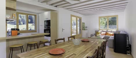 A spacious dining area with a wooden table, chairs, and a kitchen in the background.