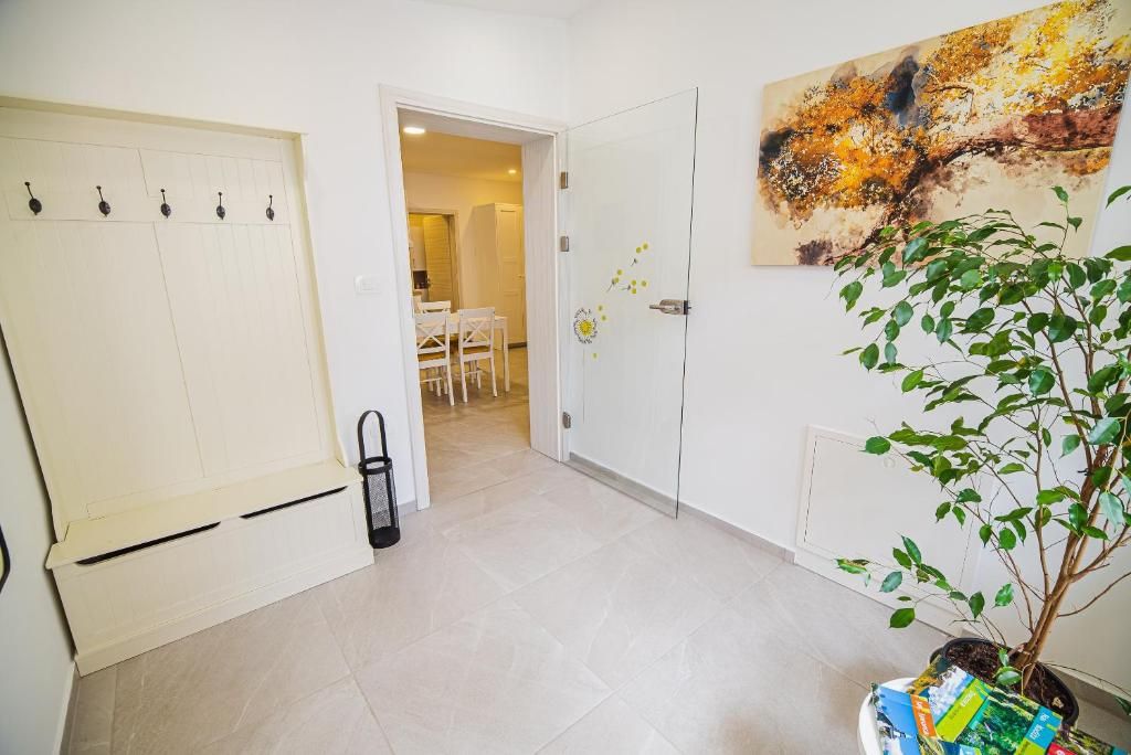 Un couloir avec une porte blanche, une plante et un tableau accroché au mur.