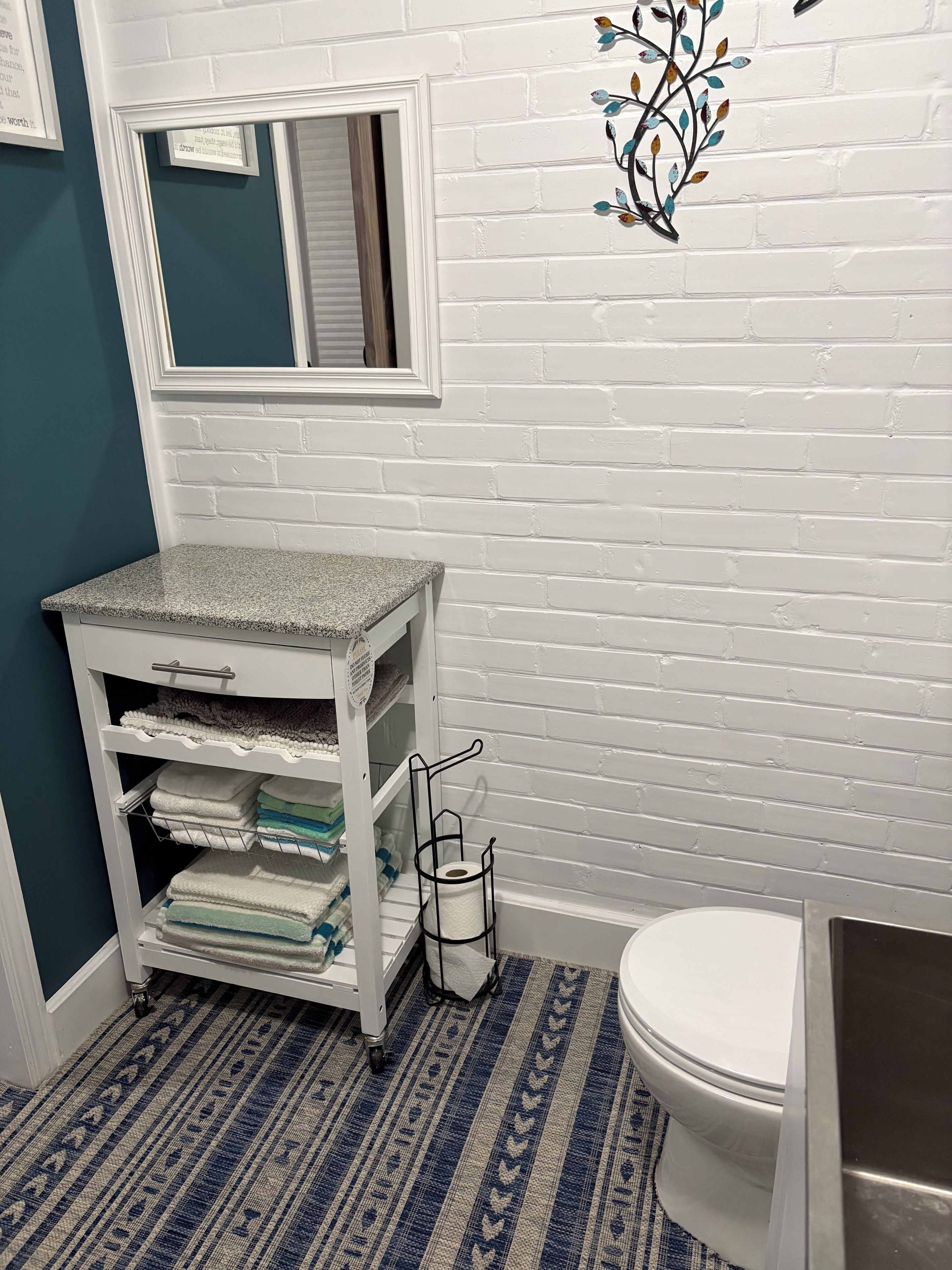 A bathroom with a white vanity, a toilet, and a blue-striped floor.