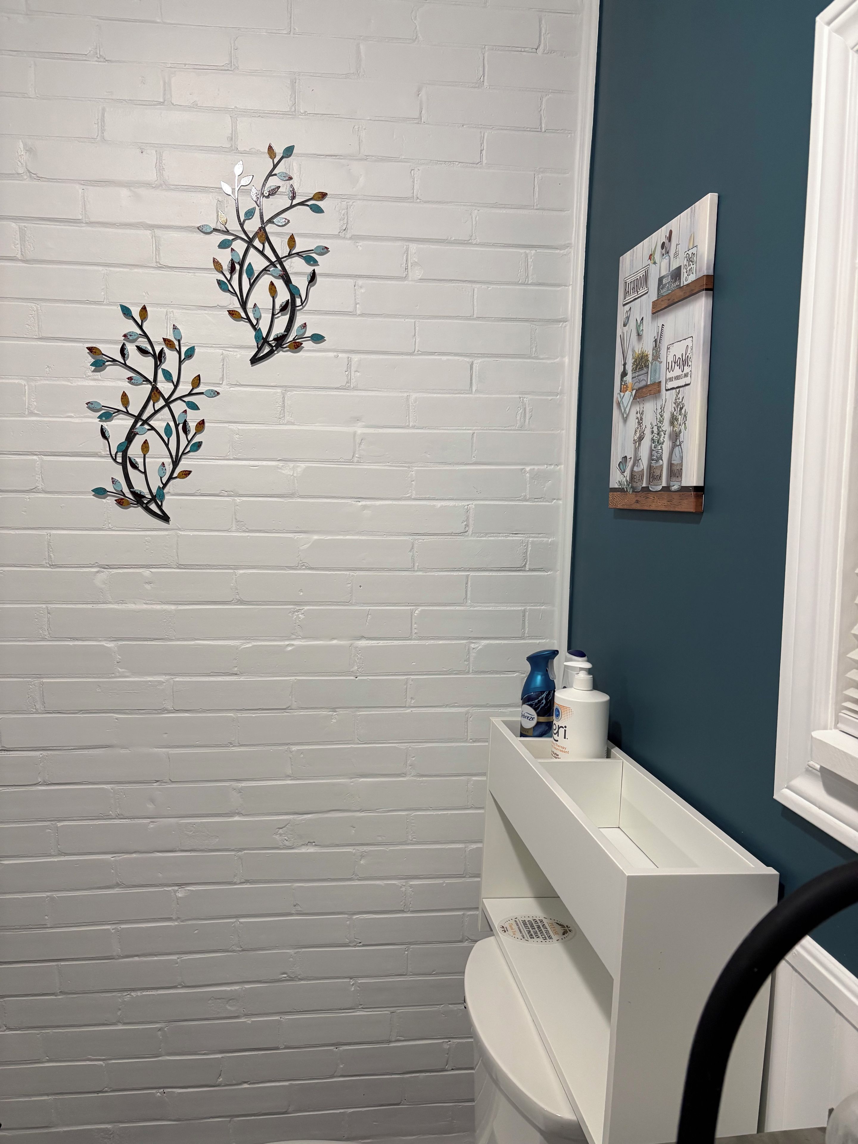 Une salle de bain avec des murs en briques blanches, un lavabo blanc et un mur d’accent bleu.