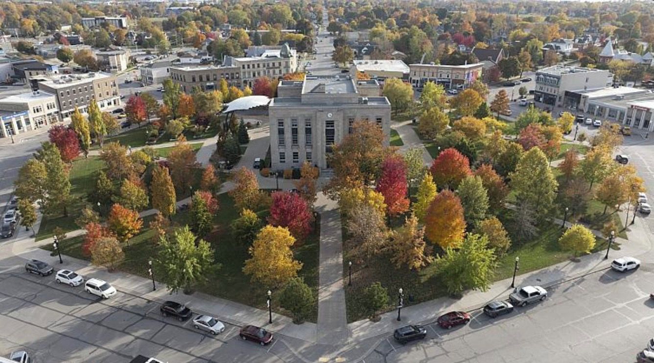 Una vista aerea di un campus con edifici, parcheggi e alberi dai colori autunnali.