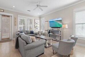 A modern living room with a grey sofa, a coffee table, and a TV mounted on the wall. - St. Somewhere (Panama City Beach)