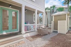 A covered porch with a white railing, a covered grill, and a small shed. - St. Somewhere (Panama City Beach)