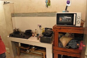 Una cocina compacta con microondas, estufa y varios utensilios.