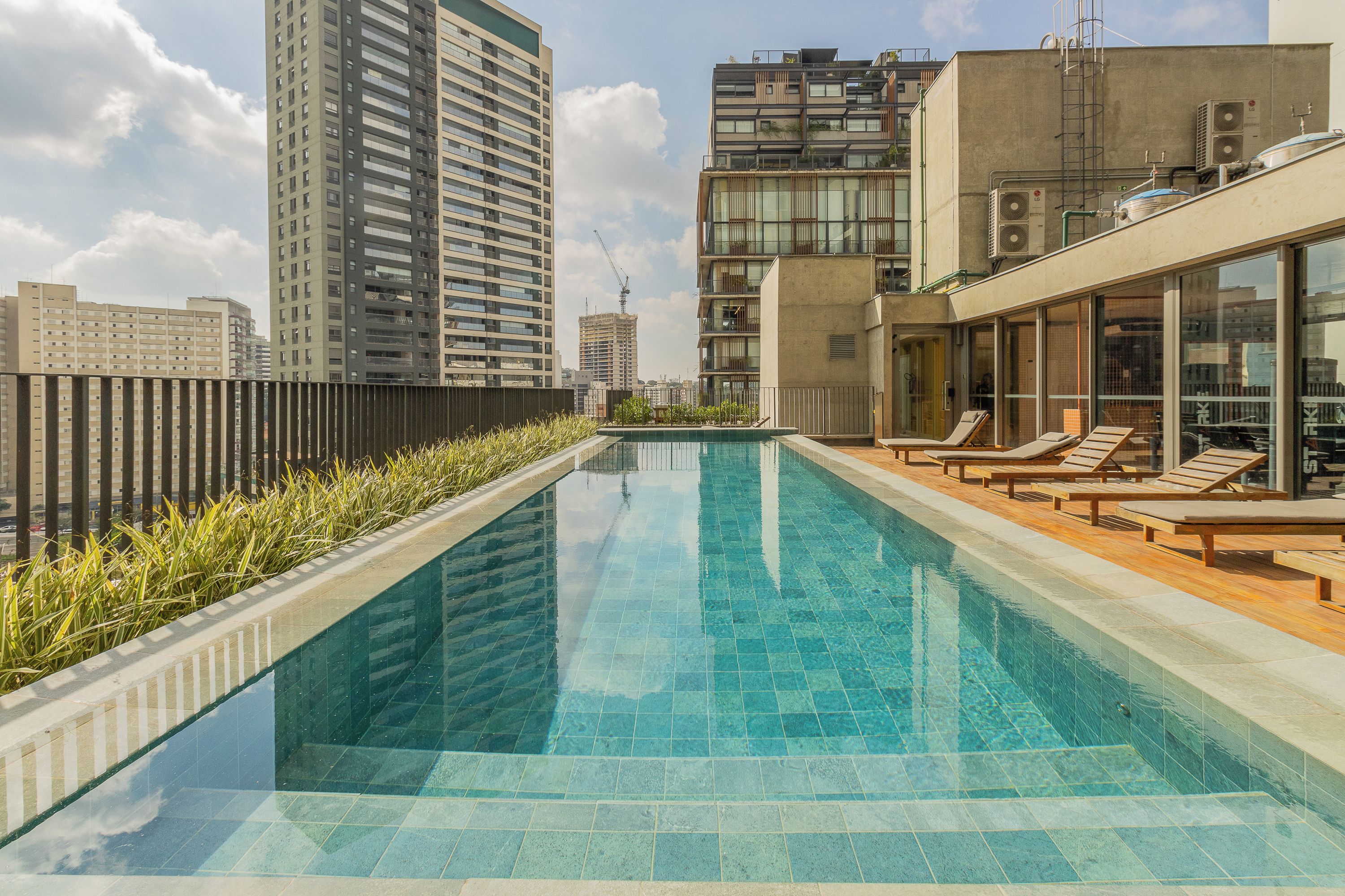 A rooftop swimming pool with lounge chairs, surrounded by high-rise buildings.