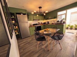 Een moderne keuken met groene kastjes, een eettafel met stoelen en een inbouwoven.
