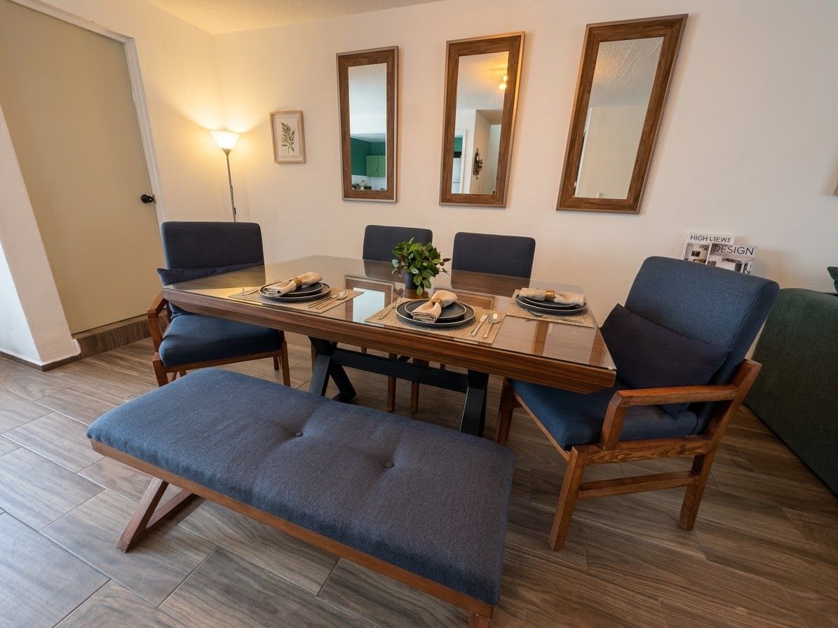 Een eetgedeelte met een houten tafel, vier stoelen, een bank en een vloerlamp.