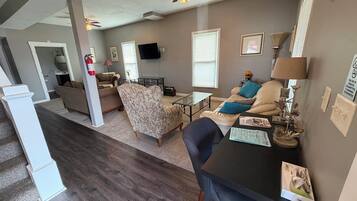 A living room with a sofa, armchairs, a coffee table, and a television.