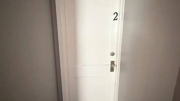 A narrow hallway with a white door marked with the number 2, leading to a room.