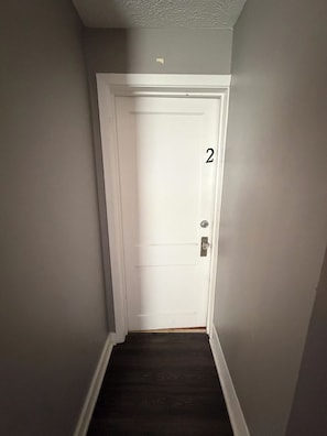 A narrow hallway with a white door marked with the number 2, leading to a room. - 2 Bedroom, main floor room with private entrance (Fairbury)