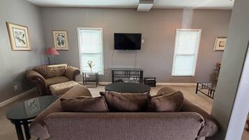A living room with a sofa, a coffee table, and a TV mounted on the wall.