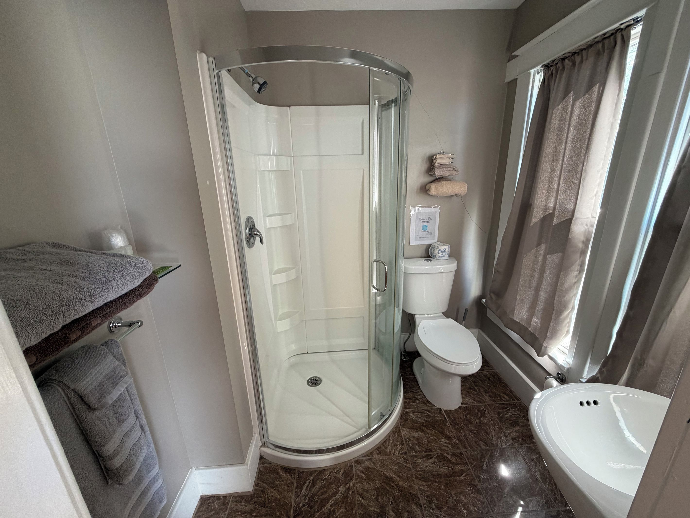 Un baño con ducha de vidrio, inodoro y lavamanos.