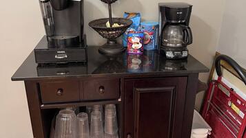 Une petite cuisine équipée d’une machine à café, d’une bouilloire, d’un panier et d’une cafetière.