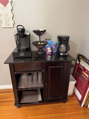 Una kitchenette equipada con cafetera, hervidor de agua, cesta y máquina de café.
