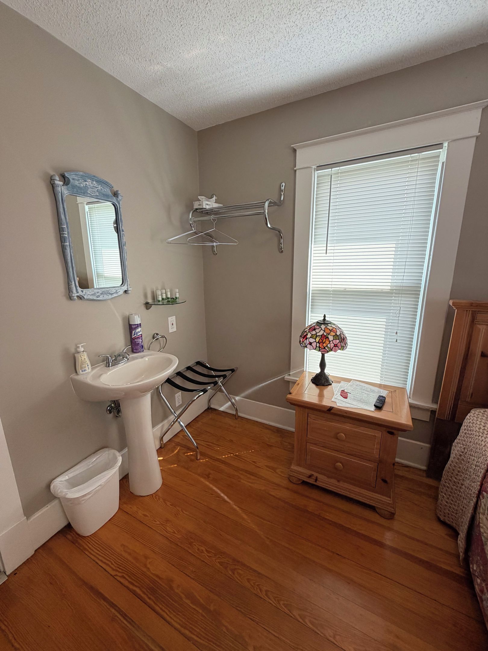 A bathroom with a sink, mirror, towel rack, and a window with blinds.