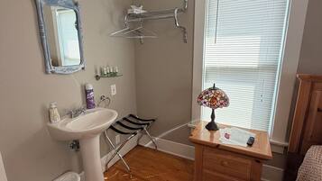 A bathroom with a sink, mirror, towel rack, and a window with blinds.