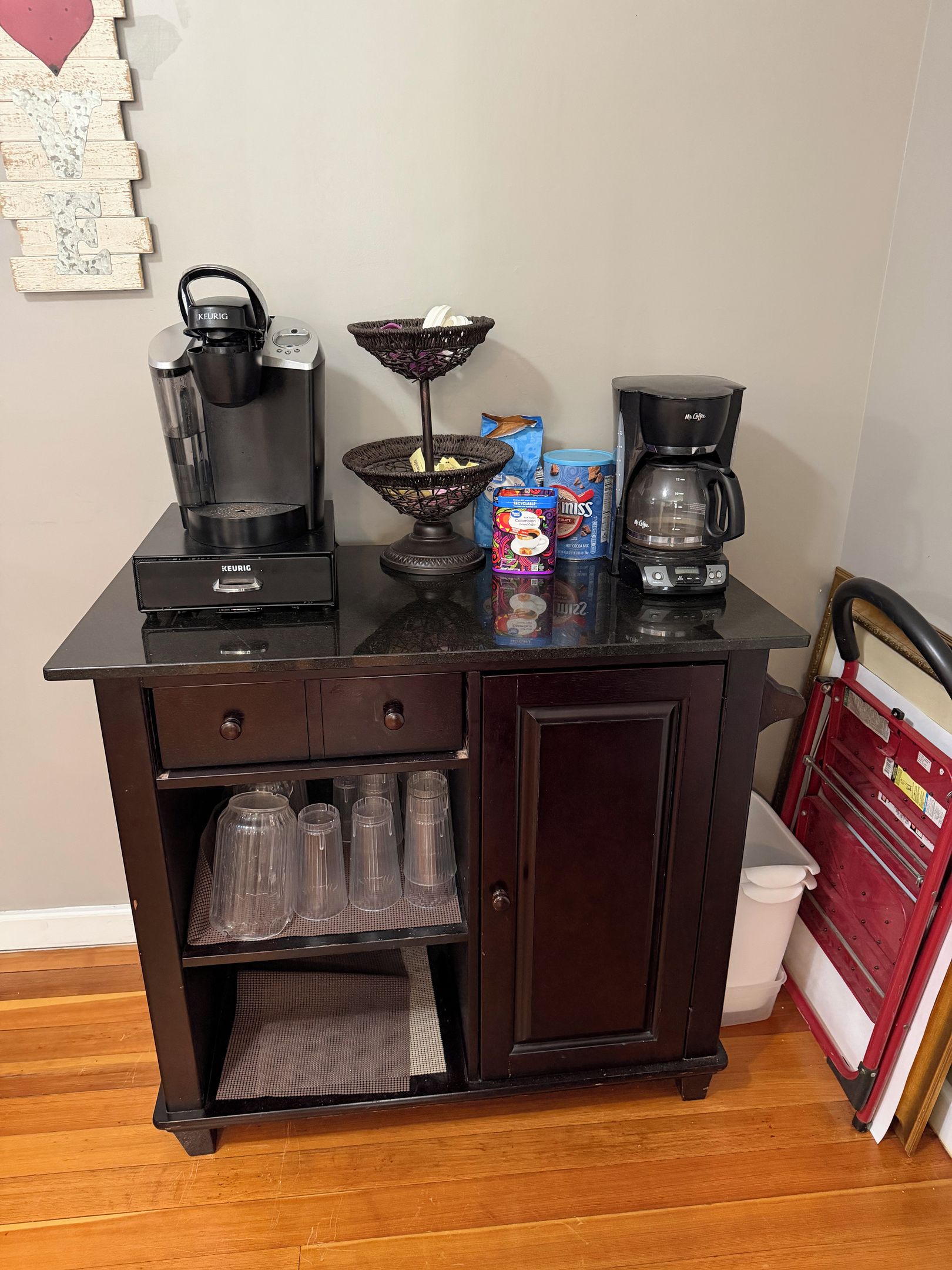 Una kitchenette con cafetera, hervidor, cesta y máquina de café.