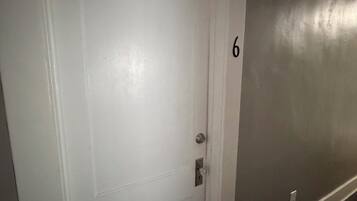 Una puerta blanca con el número 6 en la pared de al lado.