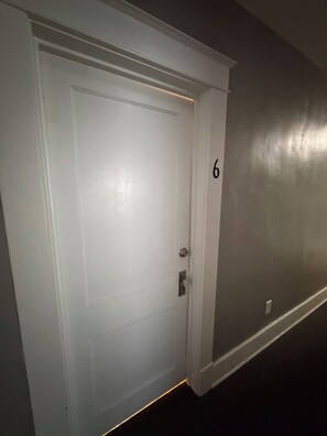 Una puerta blanca con el número 6 en la pared de al lado.