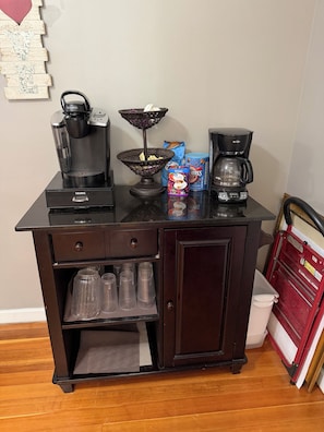 Una kitchenette equipada con cafetera, hervidor de agua, cesta y máquina de café.
