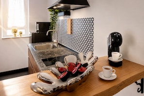A modern kitchen with a built-in sink, a coffee maker, and a tray with cups and utensils. - Vatican Sky view Spa Apartment by RHR (ROMA)