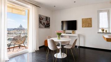 A modern living room with a dining area, a flat-screen TV, and artwork on the walls.
