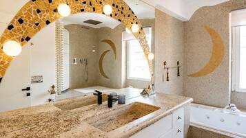 A bathroom with a large mirror, a sink, and a bathtub.