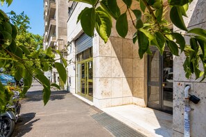 A building with a tiled facade, a door with glass panels, and a visible electrical box on the exterior wall. - Vatican Sky view Spa Apartment by RHR (ROMA)
