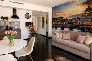 A modern living room with a large painting of a cityscape, a sofa, and a dining area with a table and chairs. - Vatican Sky view Spa Apartment by RHR (ROMA)
