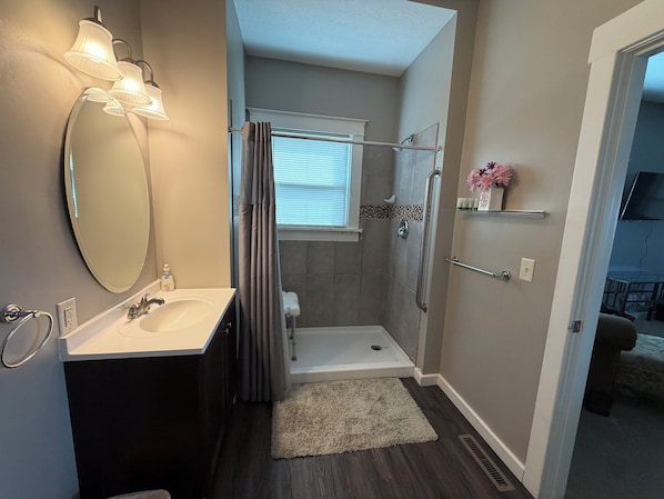 A bathroom with a shower, a toilet, a sink, and a mirror.