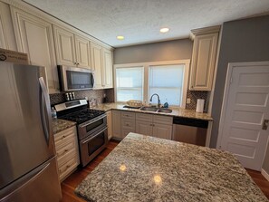A kitchen with granite countertops, stainless steel appliances, and white cabinetry. - Spacious 2 Bedroom Unit (Fairbury)