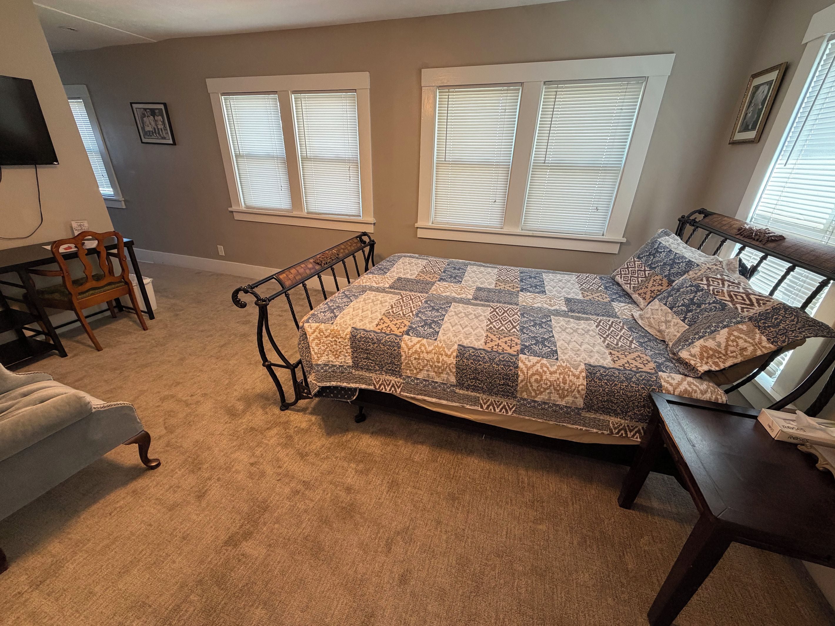 A bedroom with a bed, a chair, a table, and a television.