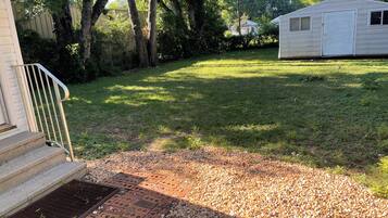 A residential property with a front yard, a small shed, and a staircase leading to a door.