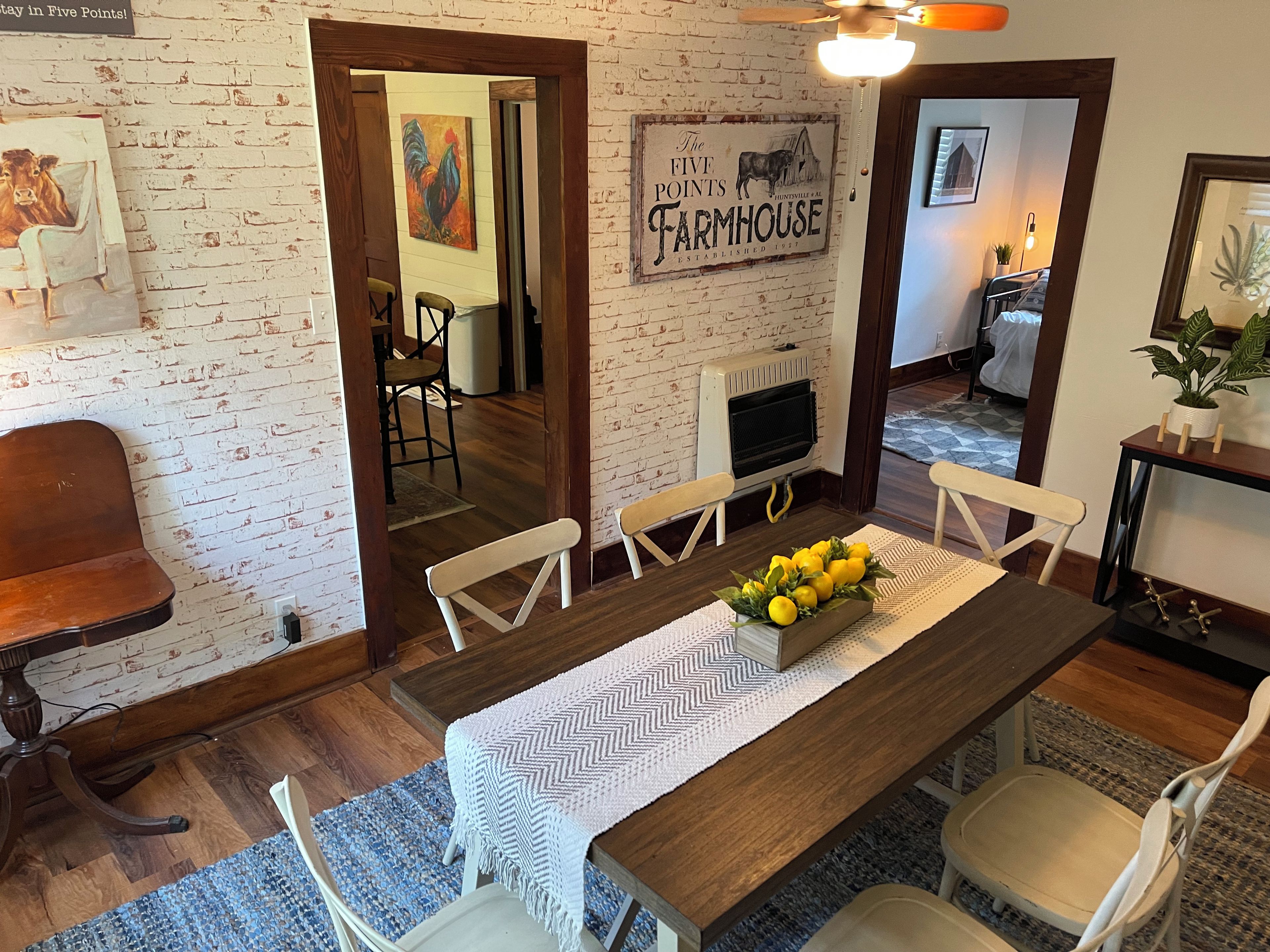 Un comedor con mesa de madera, sillas blancas y un centro de mesa decorativo.
